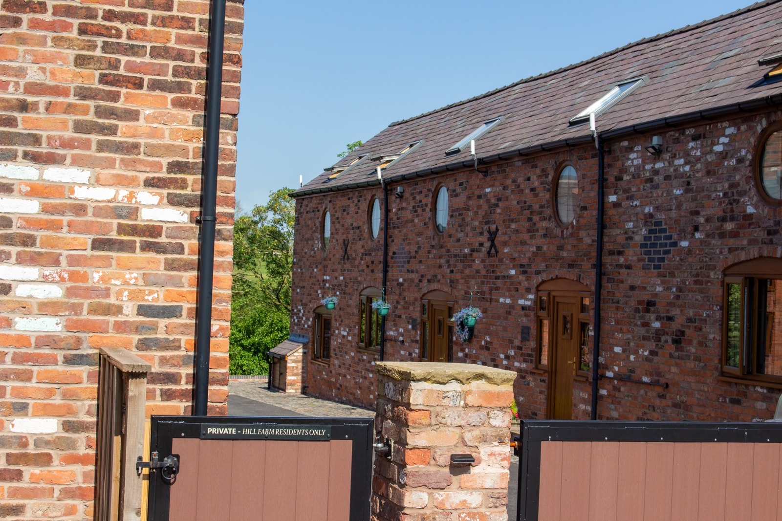 The range of converted barns with their round windows, behind the entrance gates