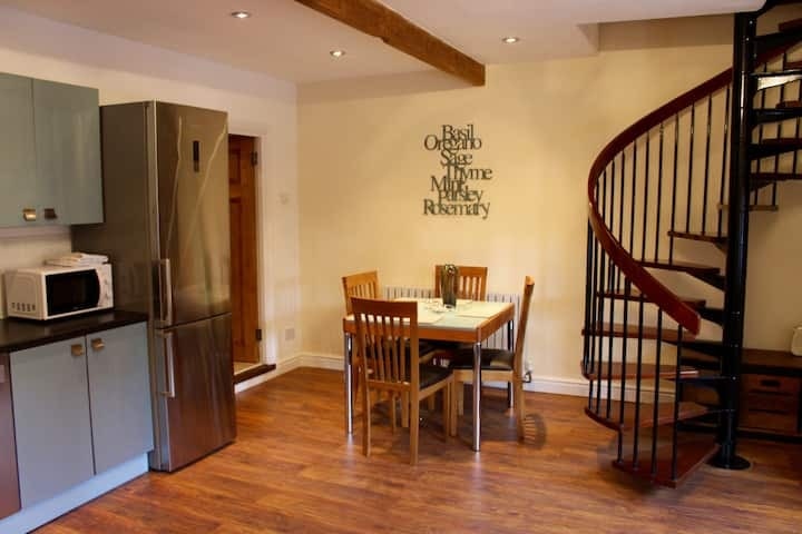 The dining table beside the spiral staircase at Oak Cottage, under exposed beams