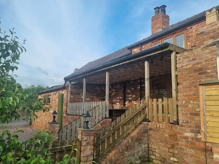 The brick frontage and covered veranda seen from the garden fence