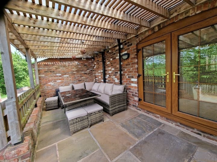 Rattan seating under the pergola on the flagged terrace at Orchard House