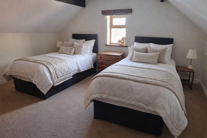 A double bedroom in soft cream, with a pair of armchairs by the window