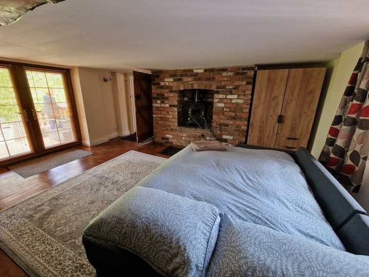 A bedroom against exposed brick, with a log burner set into the wall