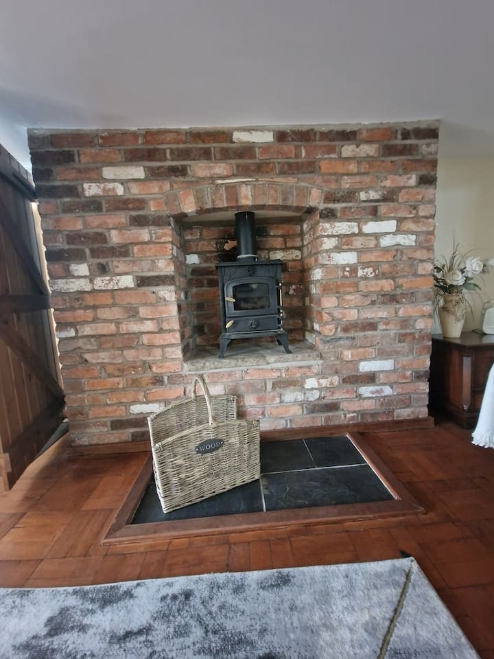 The brick fireplace and log burner, with a log basket on the hearth