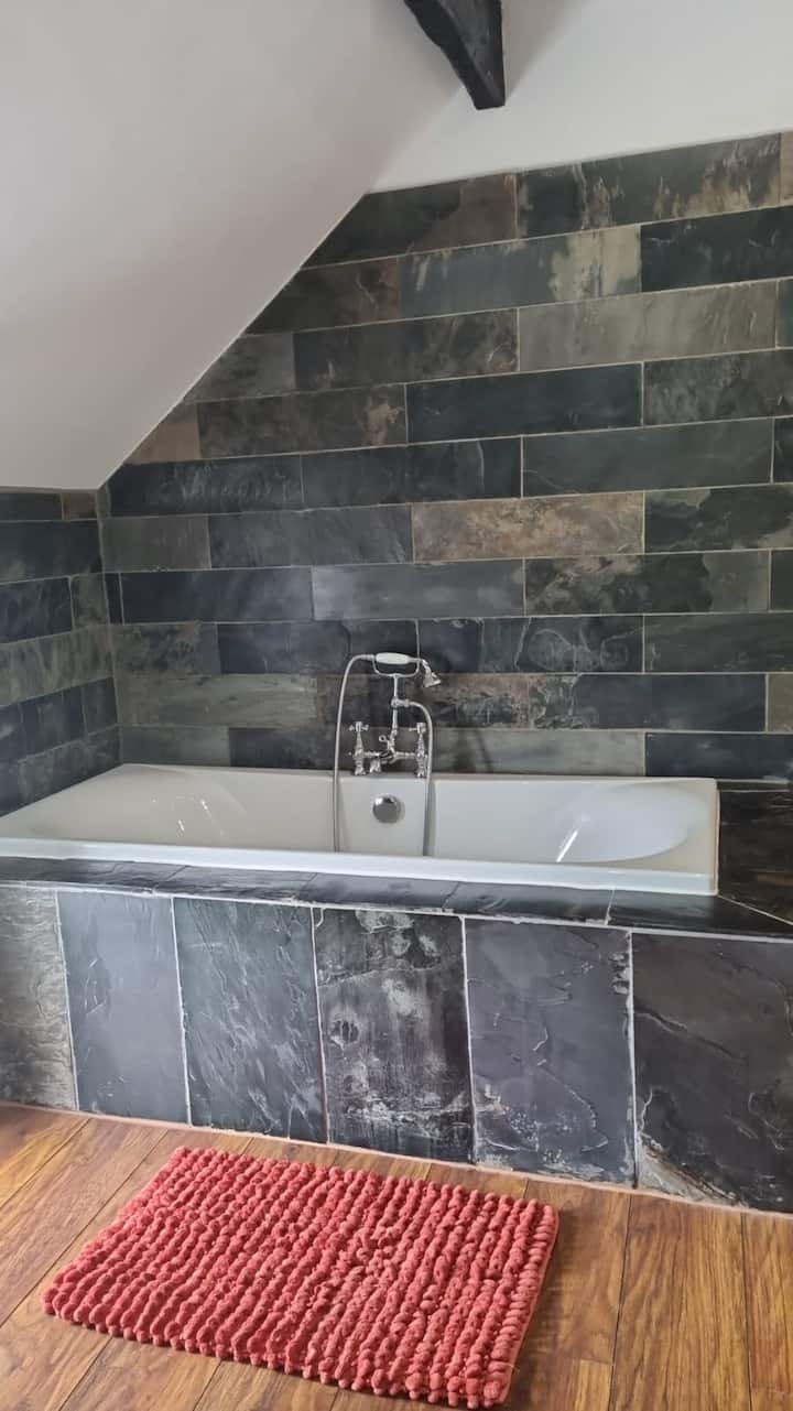 The slate-tiled bathroom, with a bath beneath the window