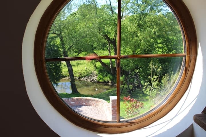The round barn window at Rose Cottage, looking out over the garden and pond