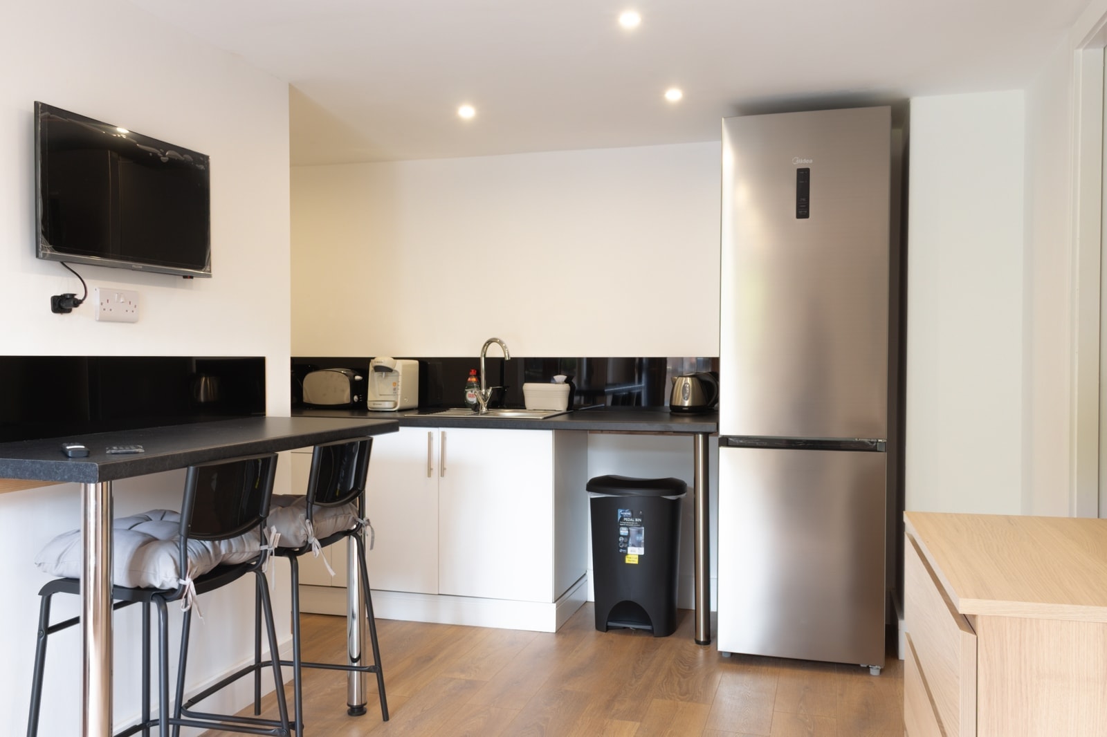 The kitchen run with its tall fridge freezer and wooden floor