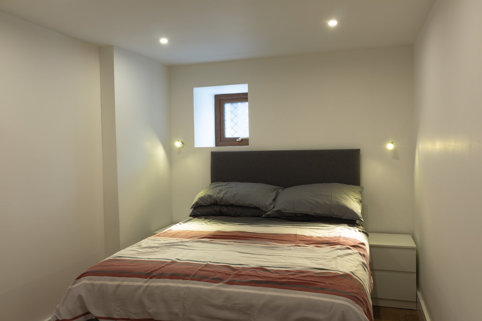 A double bedroom with a small window above the bed