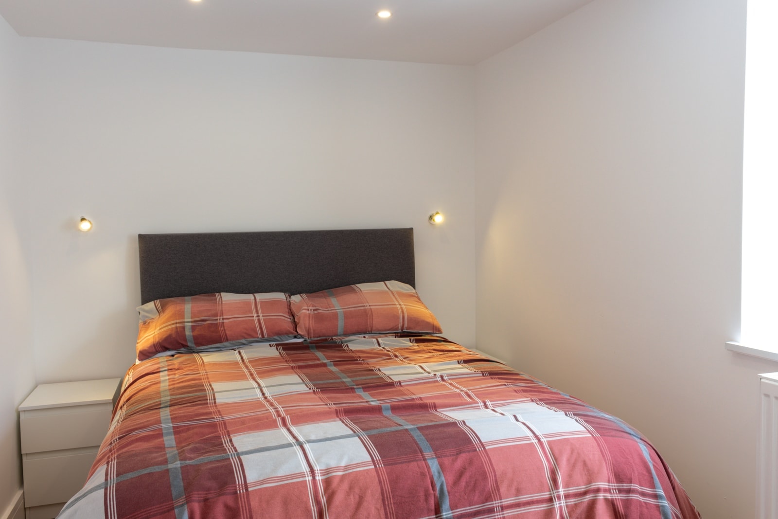 The single bedroom, with a tartan throw across the bed