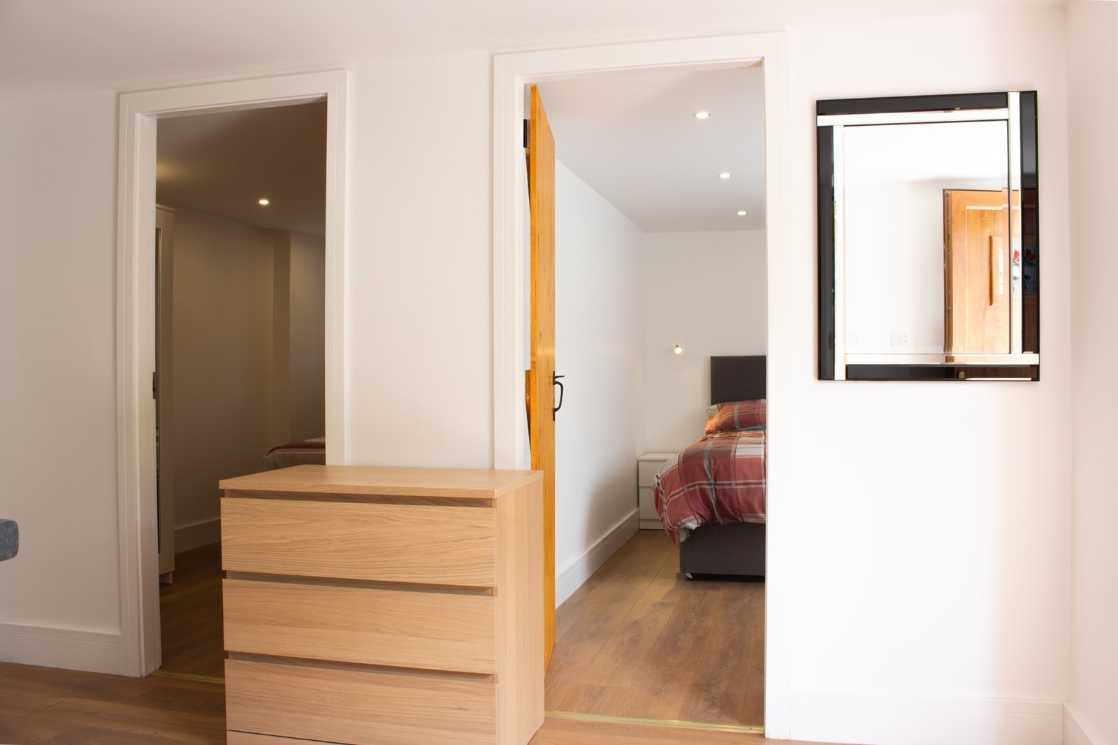 The hallway looking through to a bedroom, with a chest of drawers