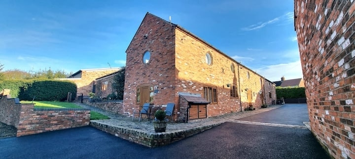 The converted brick barn with its round windows and terrace seating
