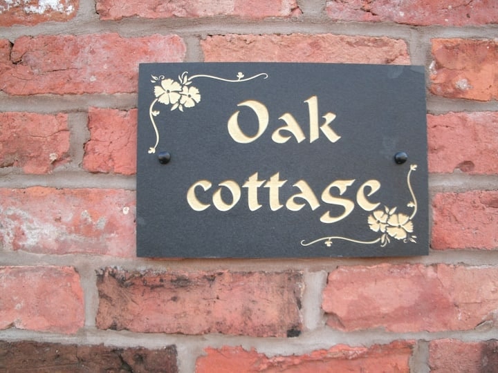 The painted slate Oak Cottage nameplate on the brickwork