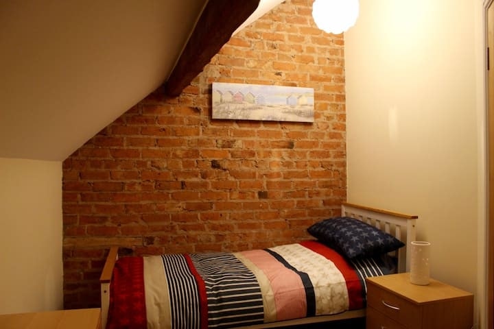 A bedroom against the barn's original exposed brickwork