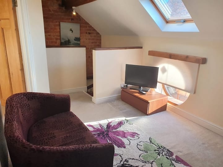 An armchair and television below the skylight on the upstairs landing