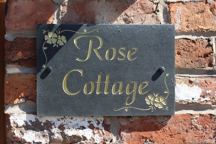 The painted slate Rose Cottage nameplate on weathered brick