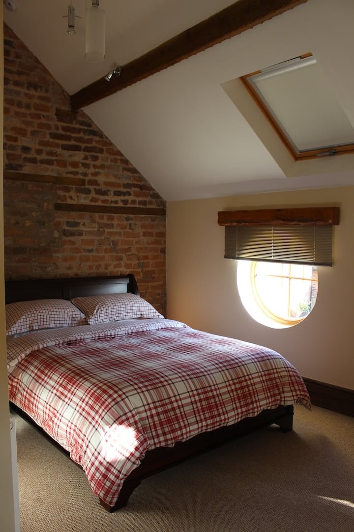 The bedroom beside its round window, made up with a tartan throw