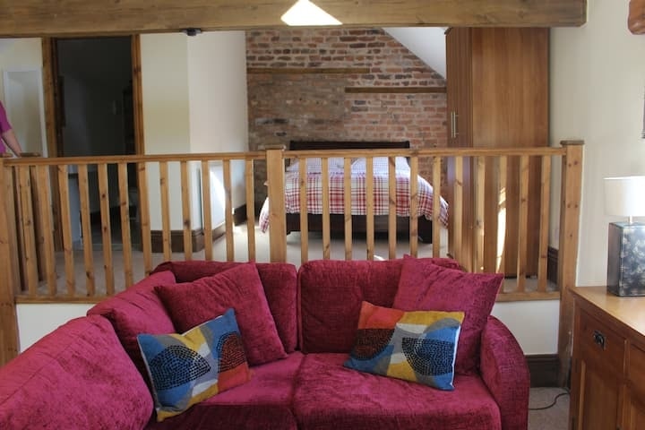 The mezzanine bedroom behind its timber balustrade, above the red sofa