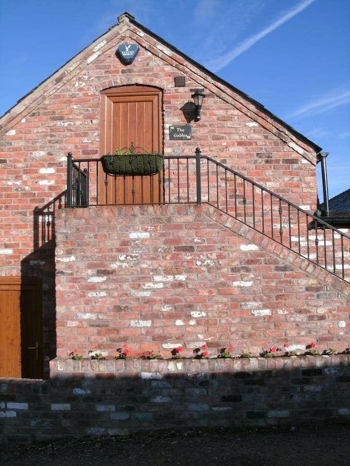 The external steps and iron railing climbing the brick wall to the first-floor door